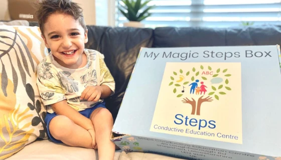 Leo with the Magic Box of helpful things to play with supplied by Steps Conductive Education Centre.